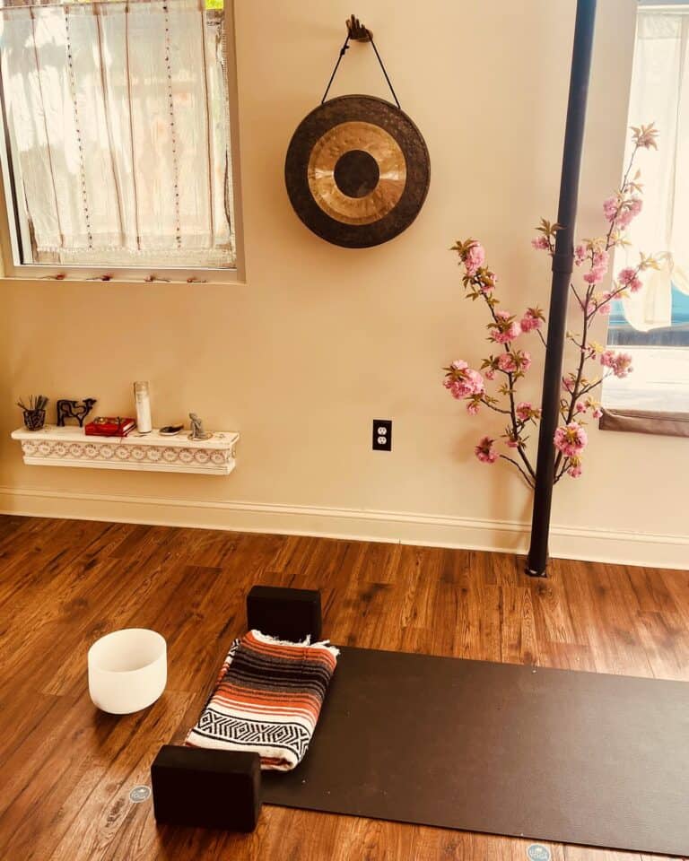 Serene yoga studio interior with pink cherry blossoms and gong, Brooklyn Bedstuy yoga class space.
