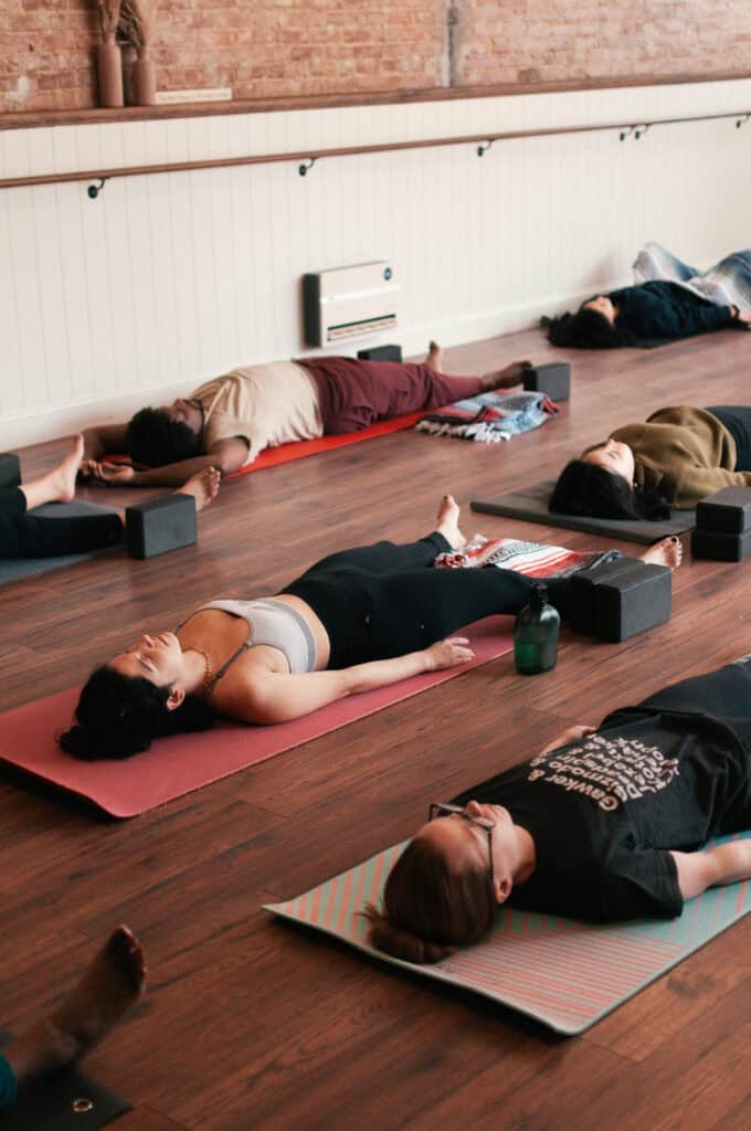 Calm yoga class at Bedstuy Yoga Brooklyn, individuals practicing relaxation and meditation in a peaceful studio environment.