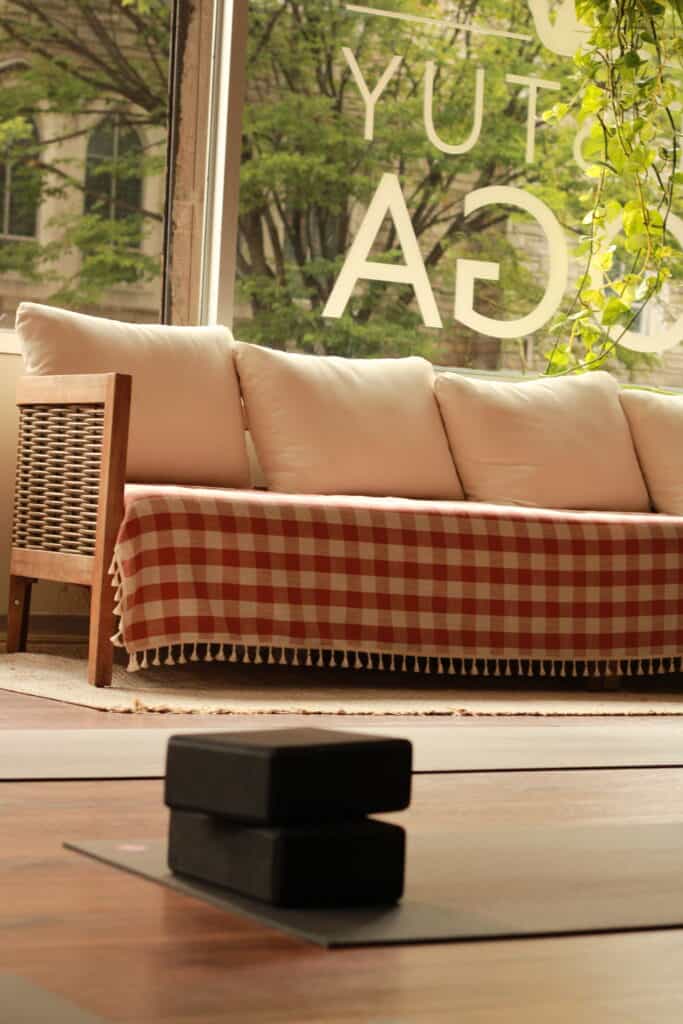 Calming yoga studio with natural light, cozy seating, and peaceful ambiance for yoga classes and relaxation.